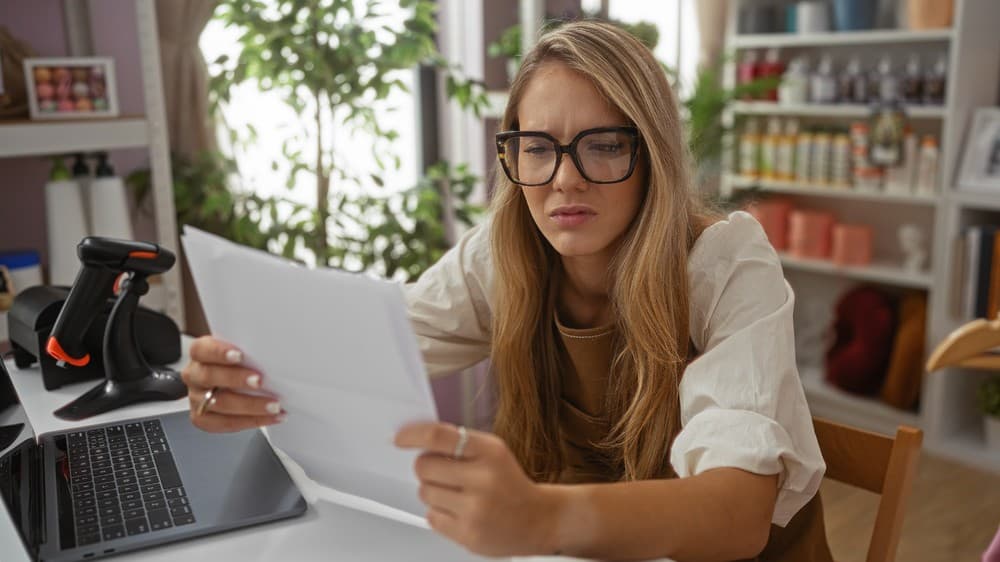 Femme préoccupée qui examine des documents après un refus d'assurance hypothécaire
